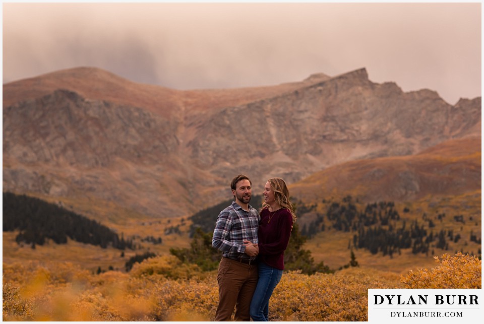 fall engagement photos in colorado couple at sunset in mountain meadow