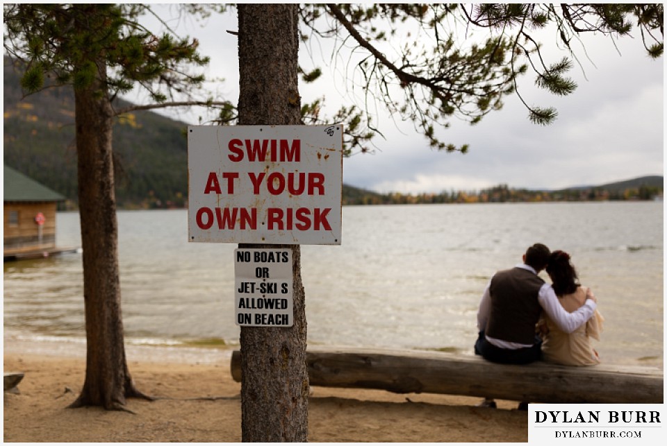 grand lake wedding elopement bride and groom on bench with swim at your own risk sign