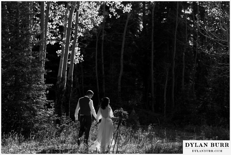 rocky mountain national park grand lake wedding elopement black and white of groom and bride walking into forest