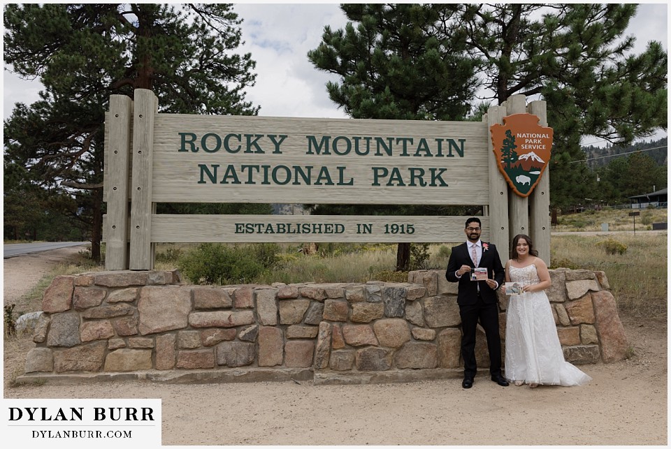 all day elopement in Rocky Mountain National Park couple at RMNP sign holding photos when they were kids