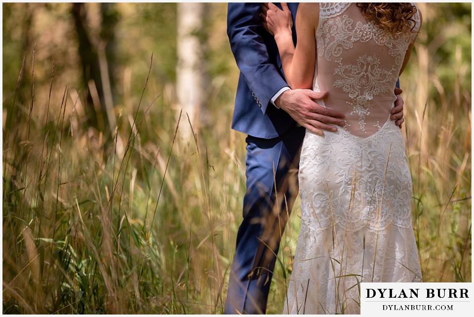 close up of brides dress details with grooms hands around her at antler basin ranch wedding