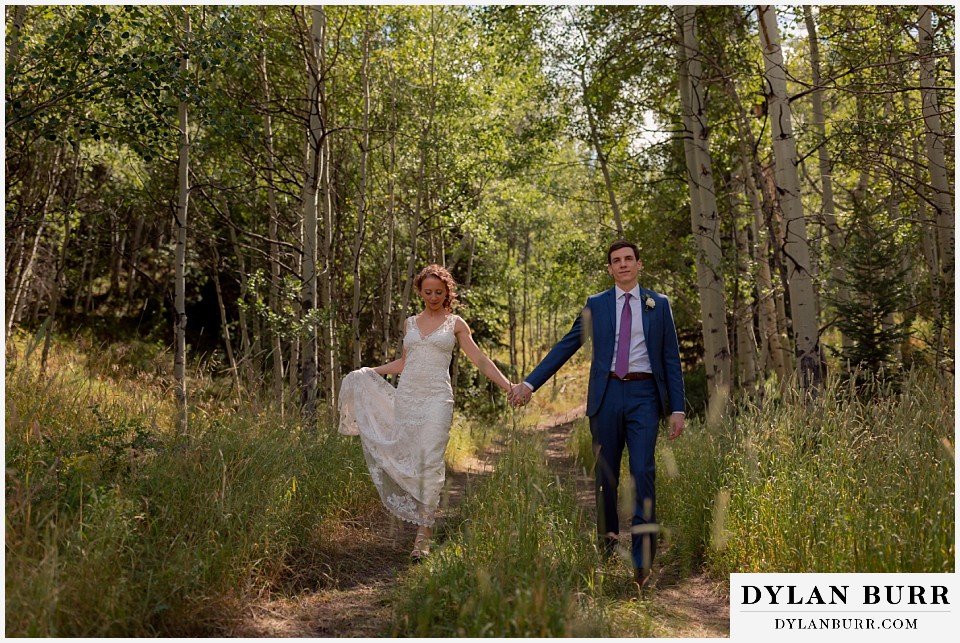 antler basin ranch wedding bride and groom holding hands in forest