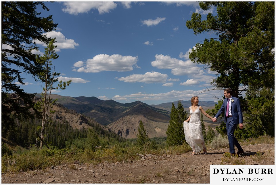 bride and groom holding hands on mountain ridge