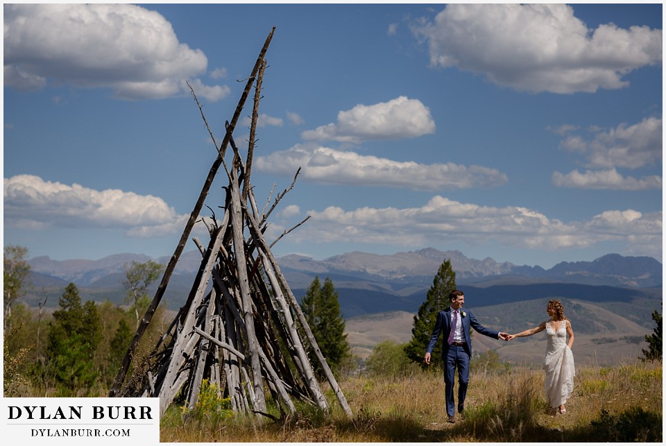 bride and groom walking near handmade tipis antler basin ranch wedding