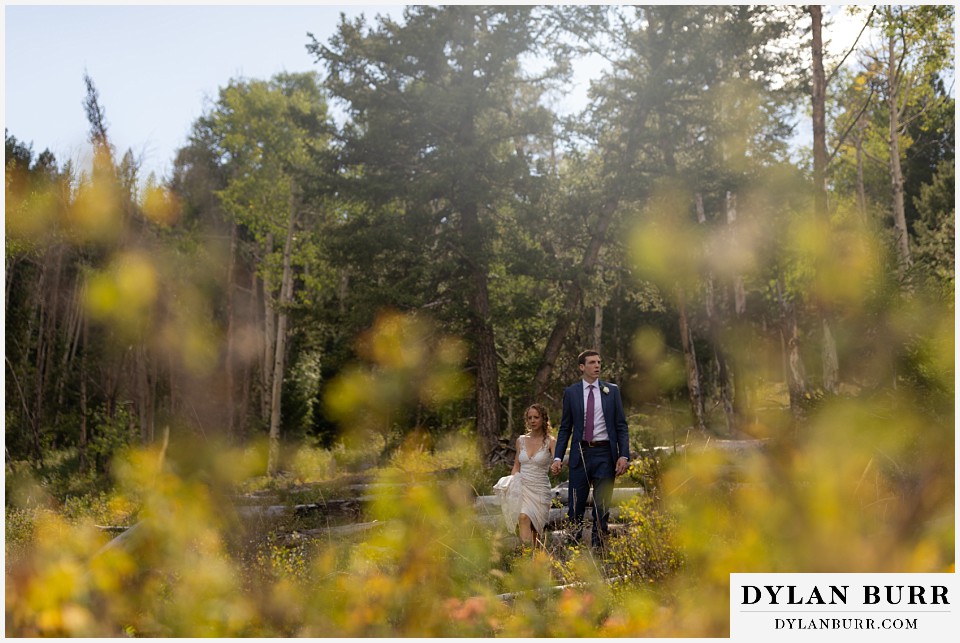 bride and groom walking together in forest at antler basin ranch wedding