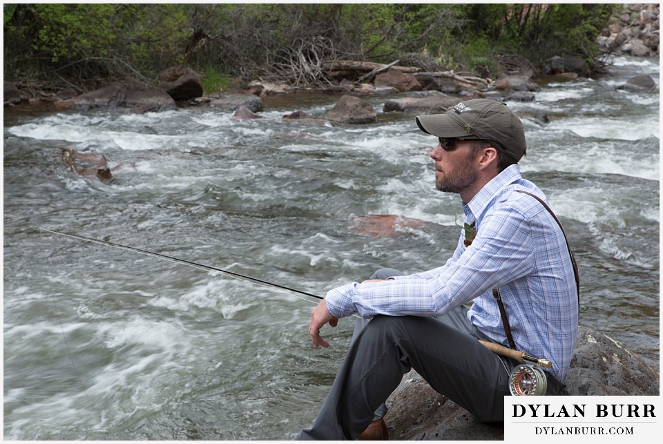 aspen wedding elopement groom sitting on rock flyfishing in river