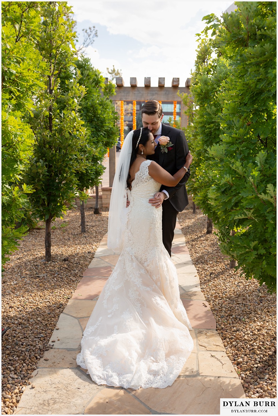 baldoria on the water wedding lakewood colorado hindu wedding newlyweds bride and groom standing on path between trees