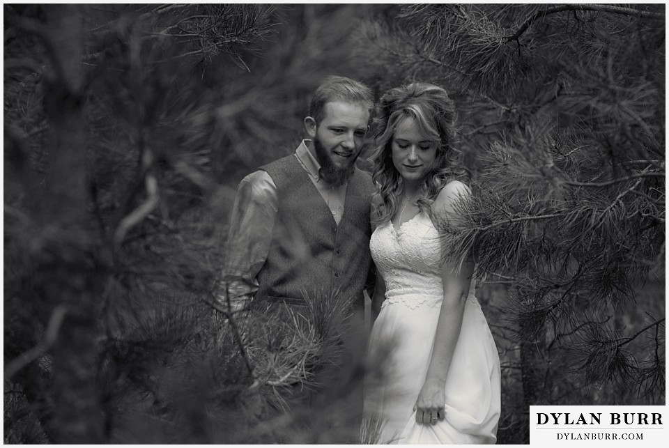 boho backyard colorado wedding black and white photo of bride and groom walking in trees