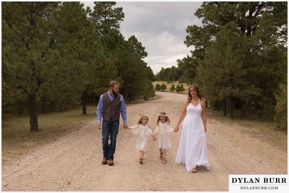 boho backyard colorado wedding bride an groom walking down road with daughters