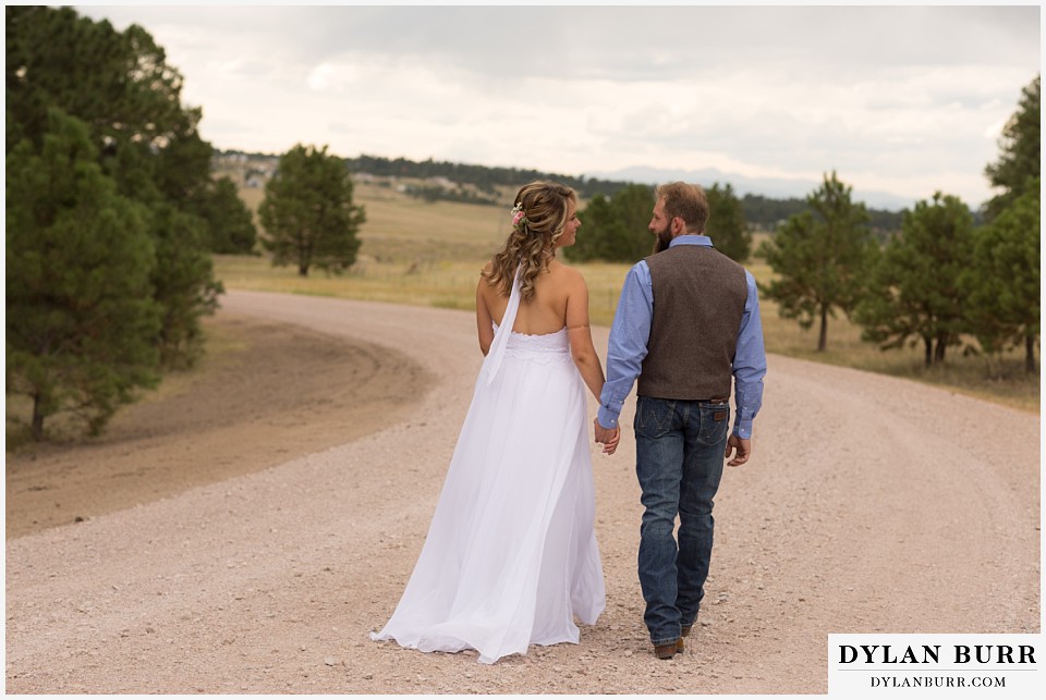 boho backyard colorado wedding bride and groom walking down dirt road