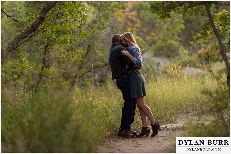 castlewood canyon engagement photos couple whispering something in his ear