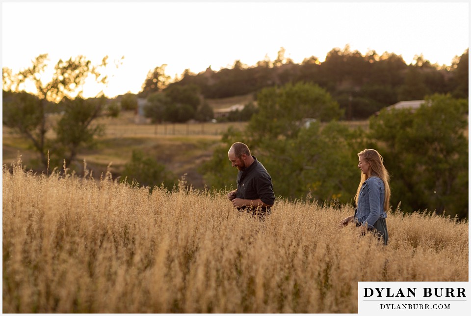 castlewood canyon engagement photos couple walking in tall wild grass field