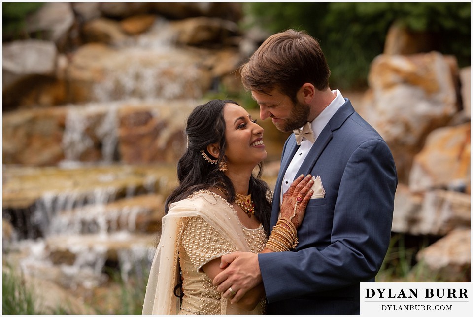 cielo at castle pines wedding colorado mountain wedding loving hindu bride and groom with waterfall in background