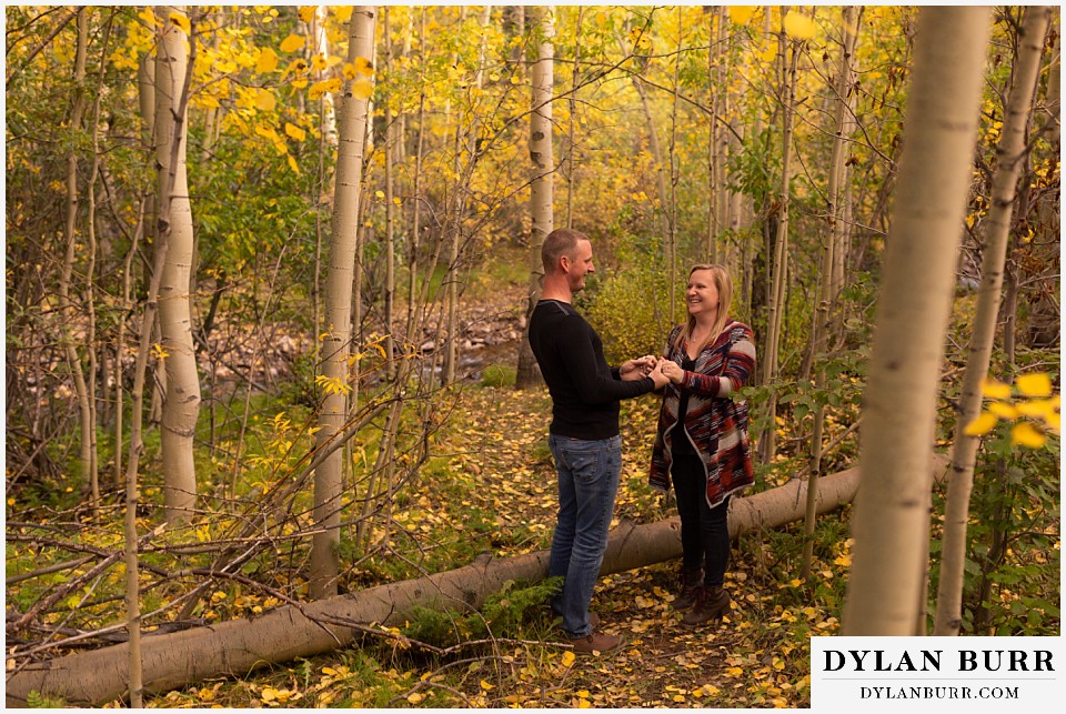 engagement photos in colorado couple in forest holding hands