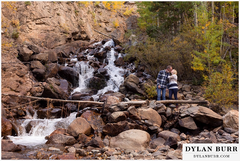 engagement photos in colorado couple kissing by large waterfall