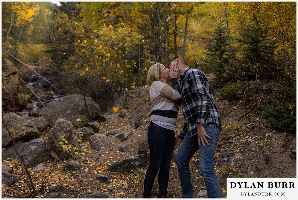 engagement photos in colorado couple kissing with leaves falling