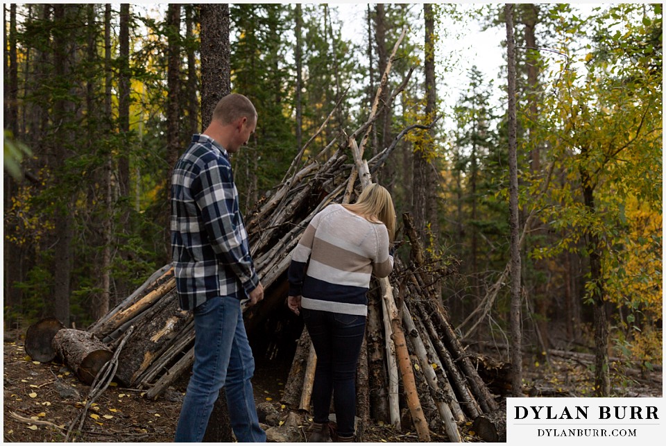 engagement photos in colorado couple discovering a handmade forest teepee tipi