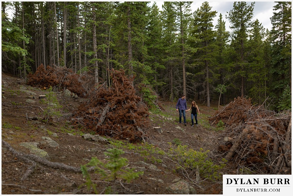 colorado mountain enagagement photo session couple walking together in dead pine trees