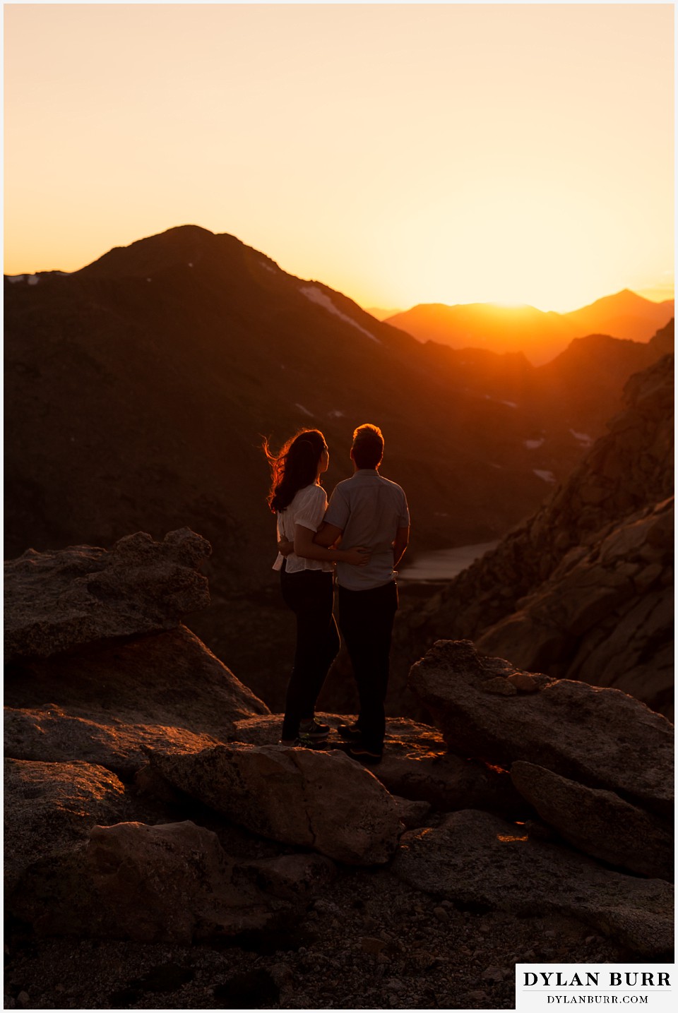colorado mountain engagement photos colorado wedding photographer dylan burr couple looking out into mountain valley at sunset in the wind