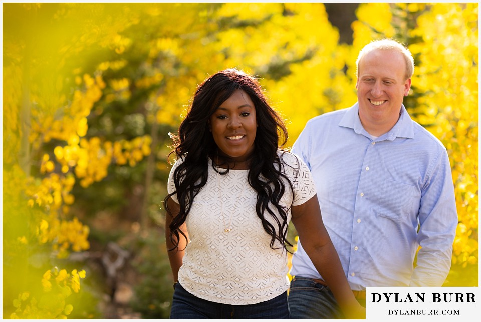 colorado mountain engagement photos couple holding hands walking in yellow aspens