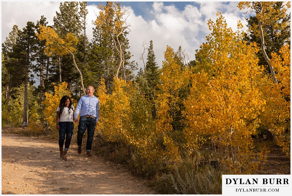 colorado mountain engagement photos couple in yellow aspens walking along road