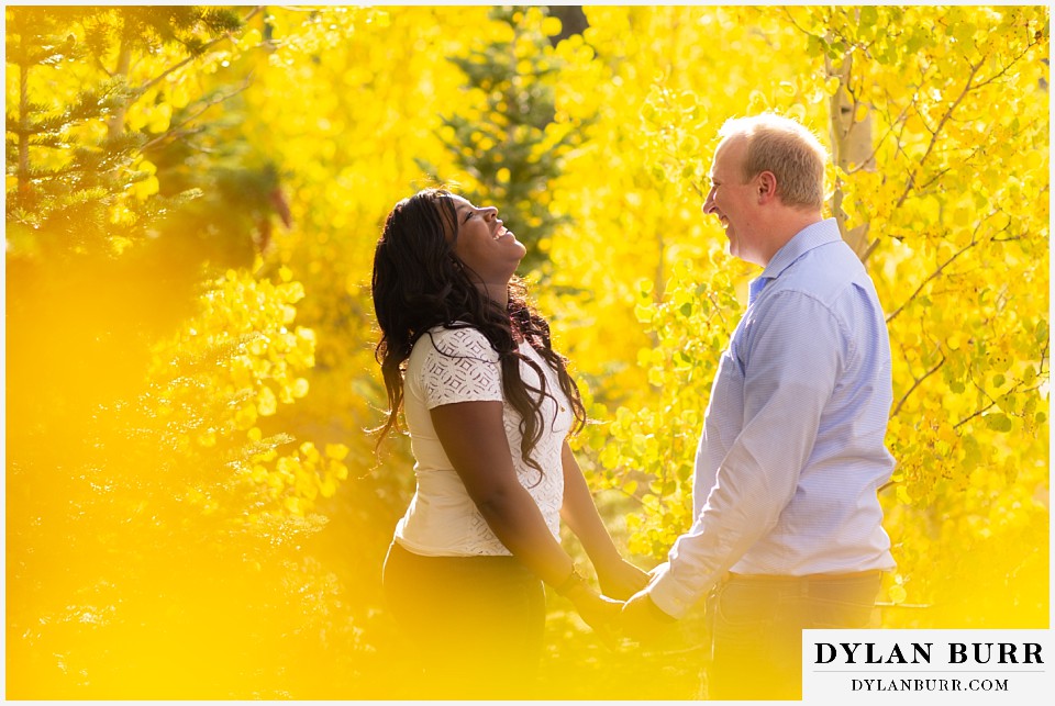 colorado mountain engagement photos bride laughing together surrounded by yellow aspen leaves