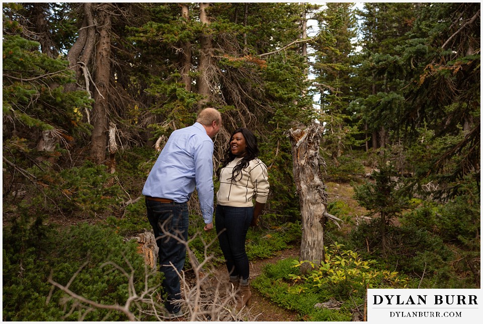 colorado mountain engagement photos groom walking up to bride in forest