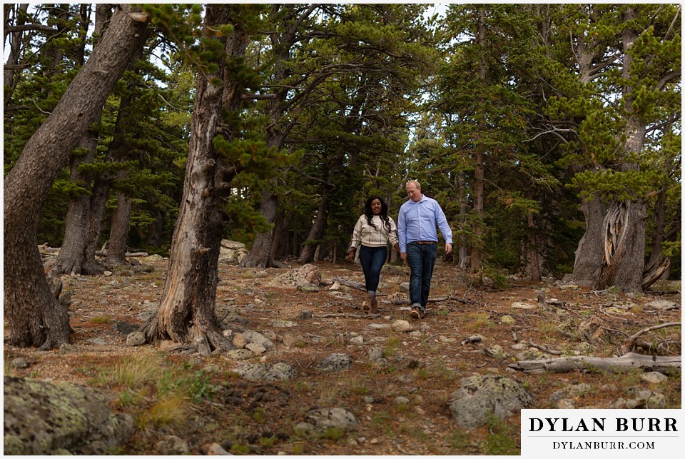 colorado mountain engagement photos walking together downhill in forest