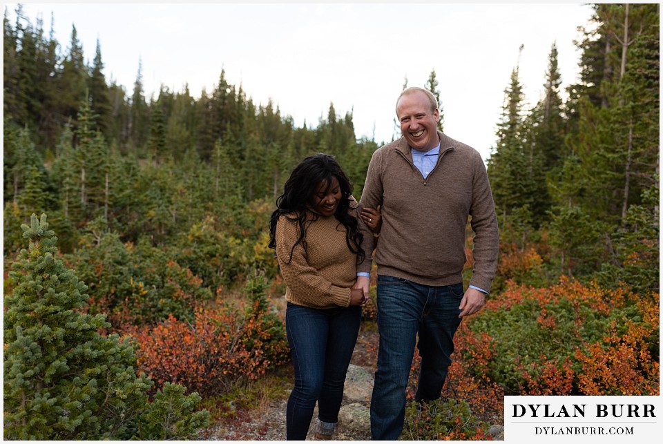 colorado mountain engagement photos couple laughing and walking in fall mountain meadow