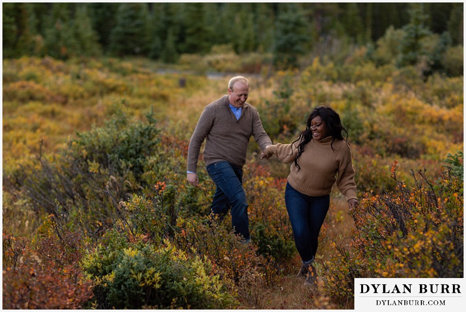 colorado mountain engagement photos bride leading groom through meadow