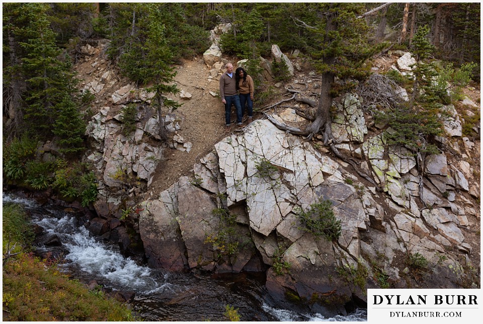 colorado mountain engagement photos couple standing on cliff by creek