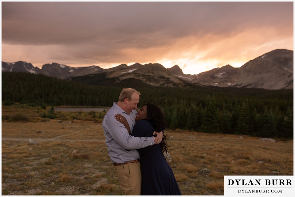 colorado mountain engagement photos couple hugging and trying to stay warm in wind