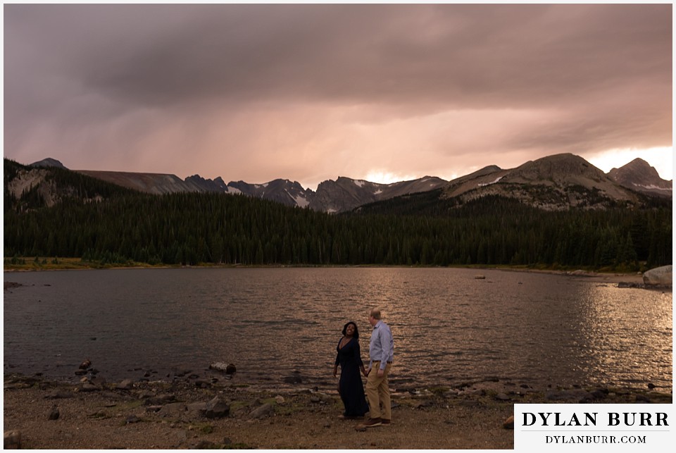 colorado mountain engagement photos bride looking back at groom by high alpine lake