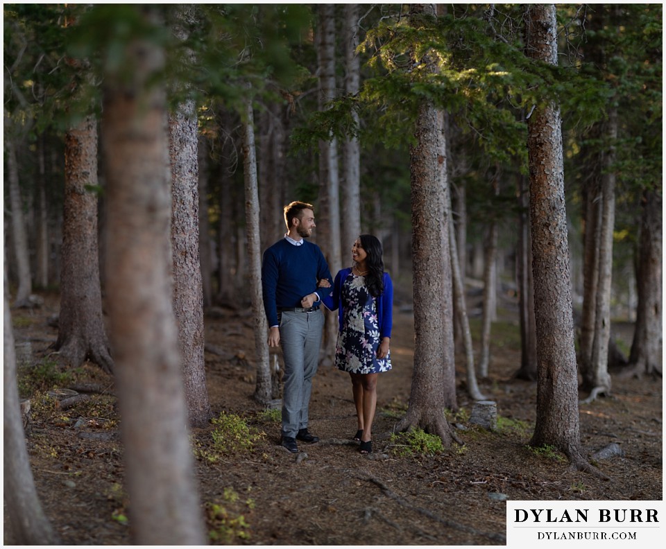 colorado engagement photos in mountains couple walking in pine tree forest