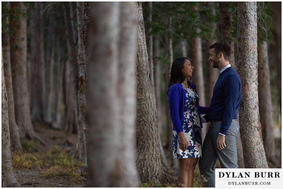 colorado engagement photos in mountains couple laughing together in tall pine trees