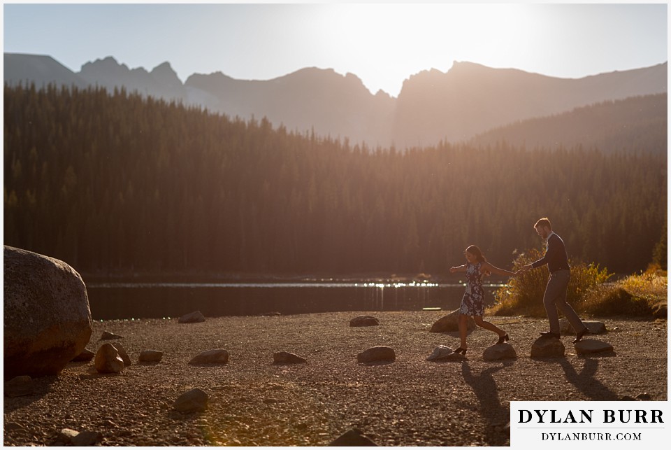 colorado engagement photos in mountains couple at sunset at lake on stepping stones