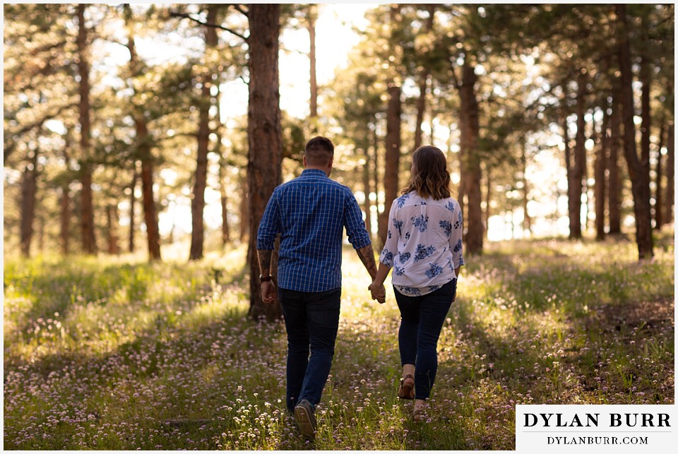 golden colorado mountain enagagement photo session couple walking with spring wildflowers around them