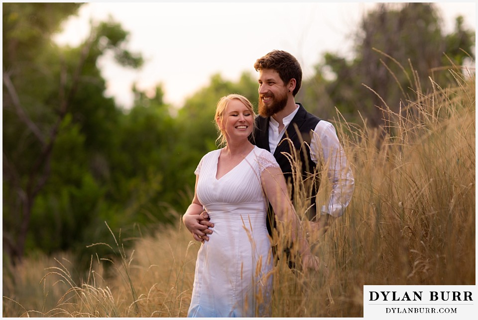 wedding couple standing together in tall grass at sunset colorado wedding
