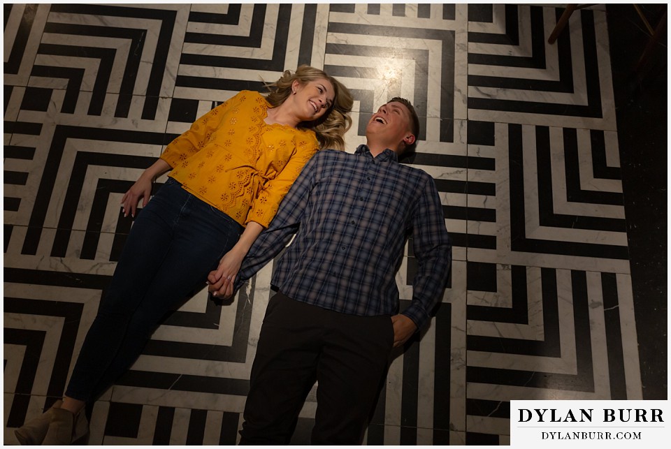 denver engagement photos dairy block downtown denver couple lying together laughing on cool floor