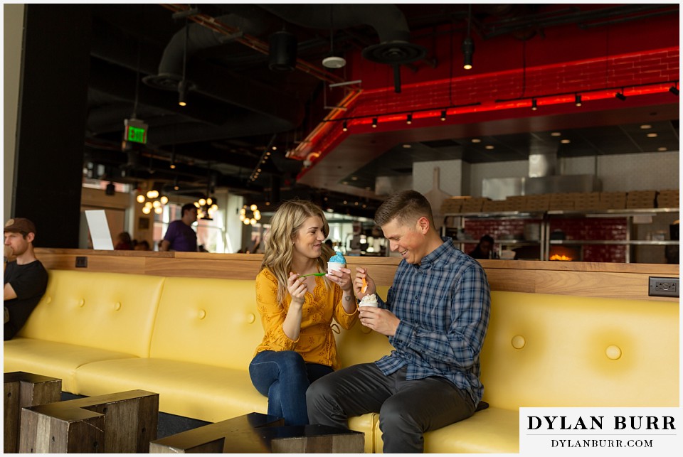 denver engagement photos dairy block downtown denver sitting together and laughing while eating some ice cream