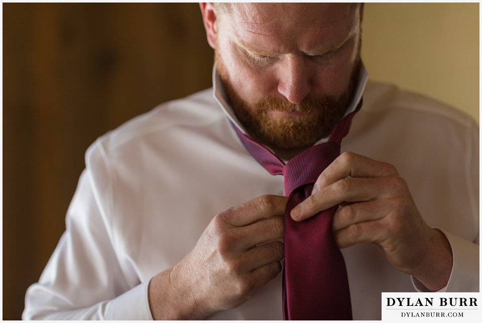 devils thumb ranch wedding in winter groom tying tie