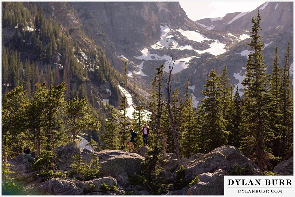 estes park engagement photos couple walking out on rocks near alpine lake