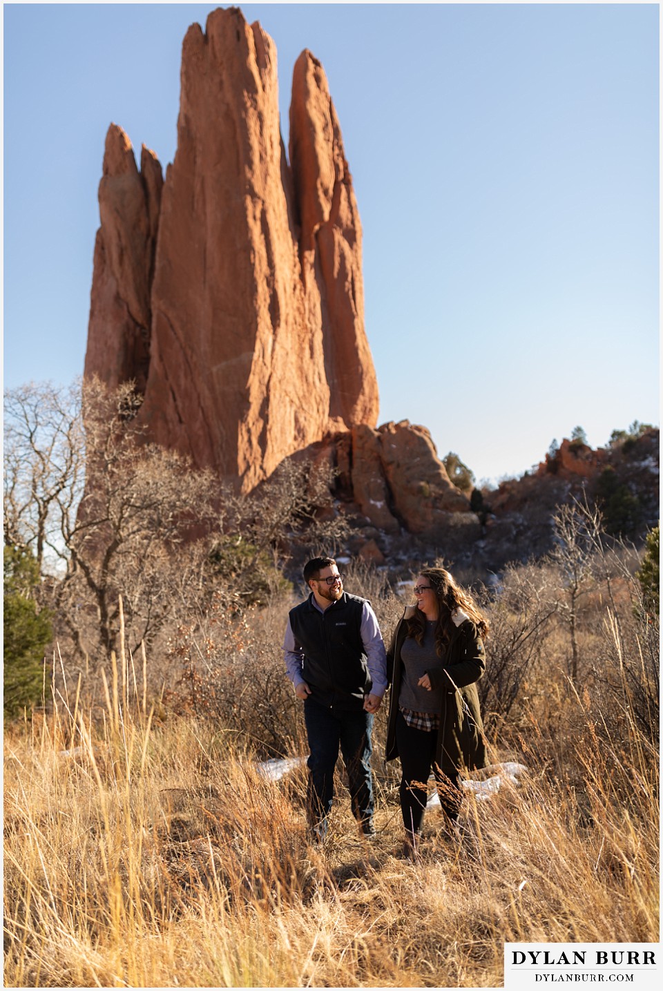 garden of the gods engagement session couple walking with extremely tall rocks in the background