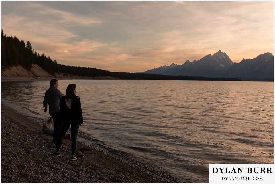 grand teton wedding anniversary photos couple skipping stones at sunset on Jackson Lake