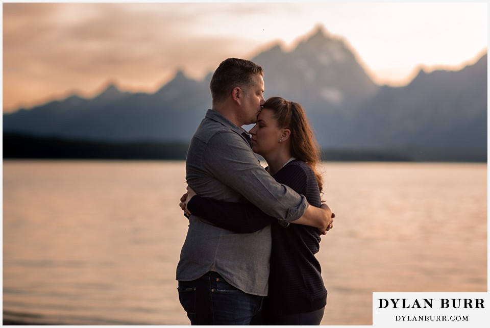 grand teton wedding anniversary photos couple he hisses her forehead at sunset