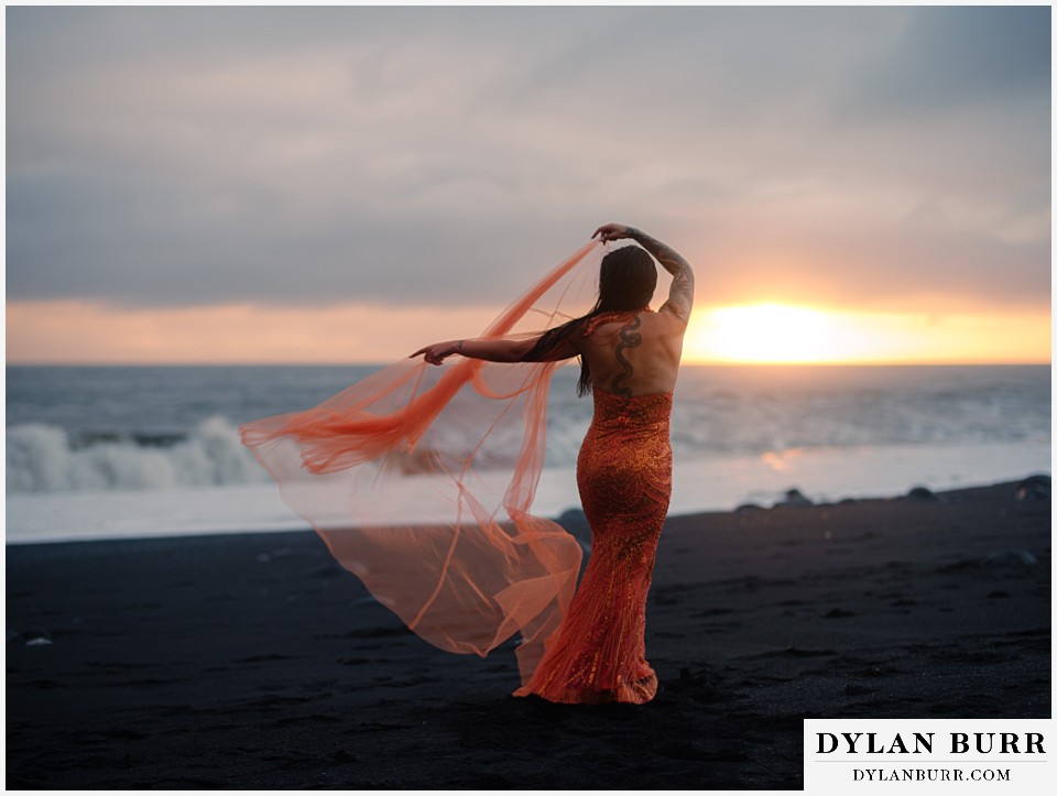 iceland elopement at reynisfjara beach orange dress dancing in the wind