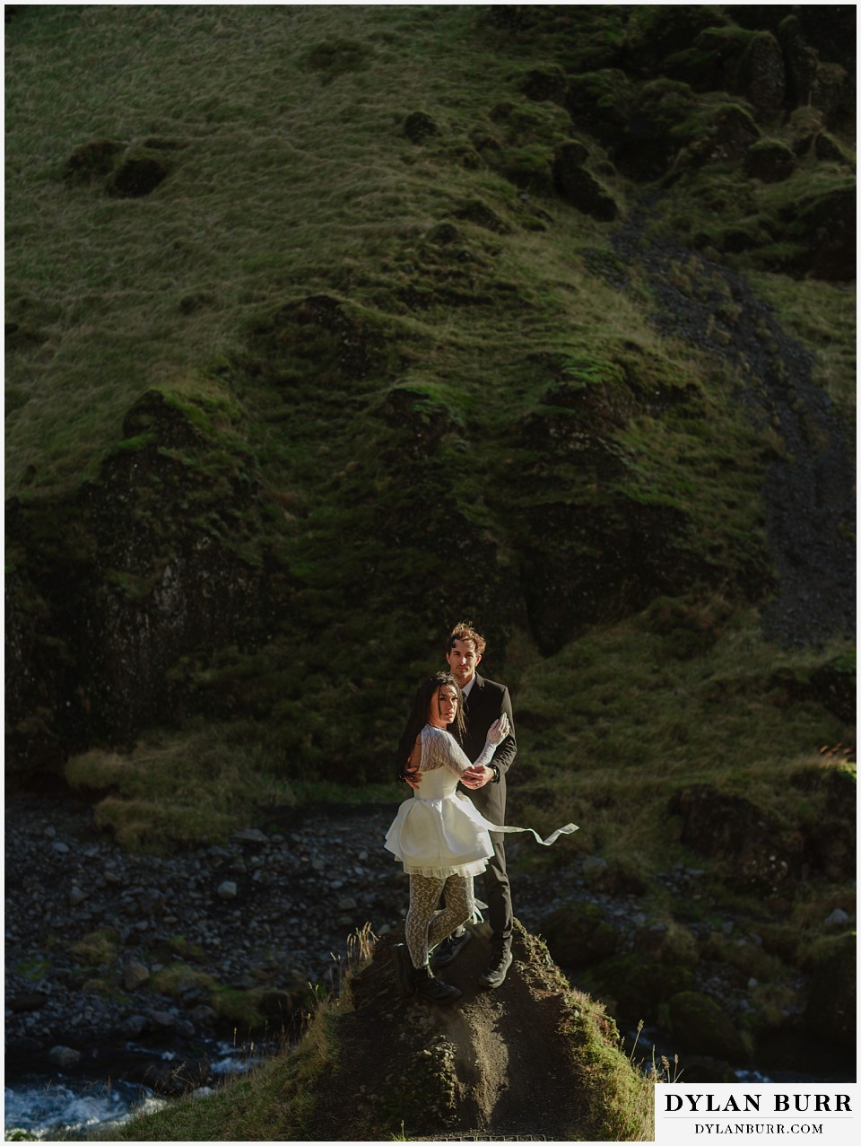 Iceland elopement wedding waterfall canyon near selfoss couple standing together on small peak with grass around