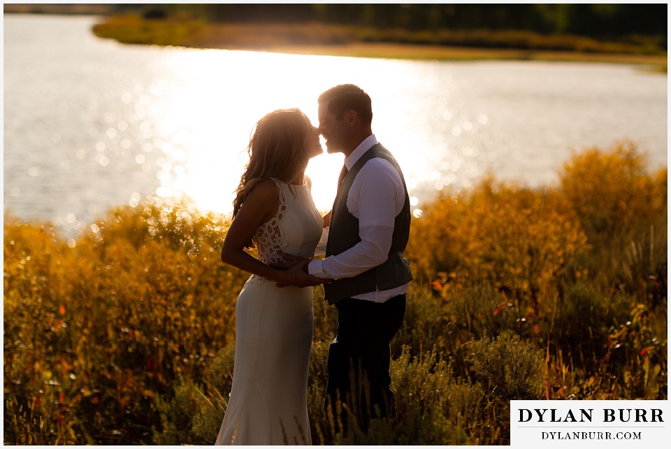 jackson lake lodge wedding grand tetons wyoming bride and groom kissing at sunset at the snake river