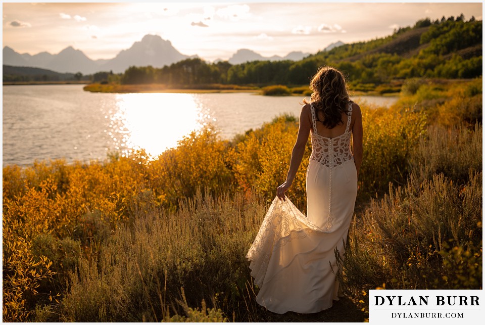 jackson lake lodge wedding grand tetons wyoming bride walking into the sunlight along snake river