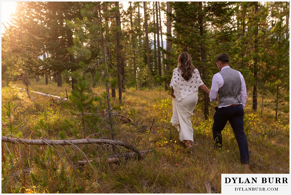 jackson lake lodge wedding grand tetons wyoming bride and groom walking into forest at sunset